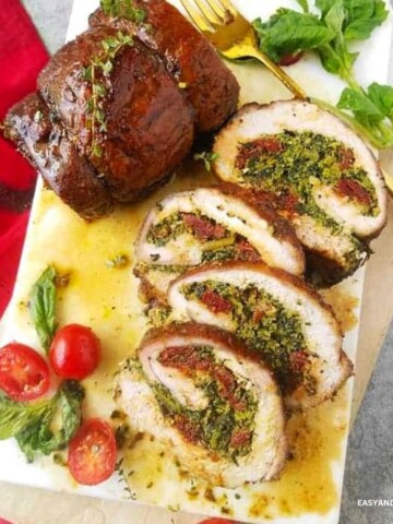 Partially sliced stuffed pork loin on a cutting board.