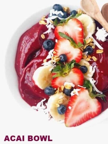 close up of acai bowl with coconut flakes, sliced bananas, and berries
