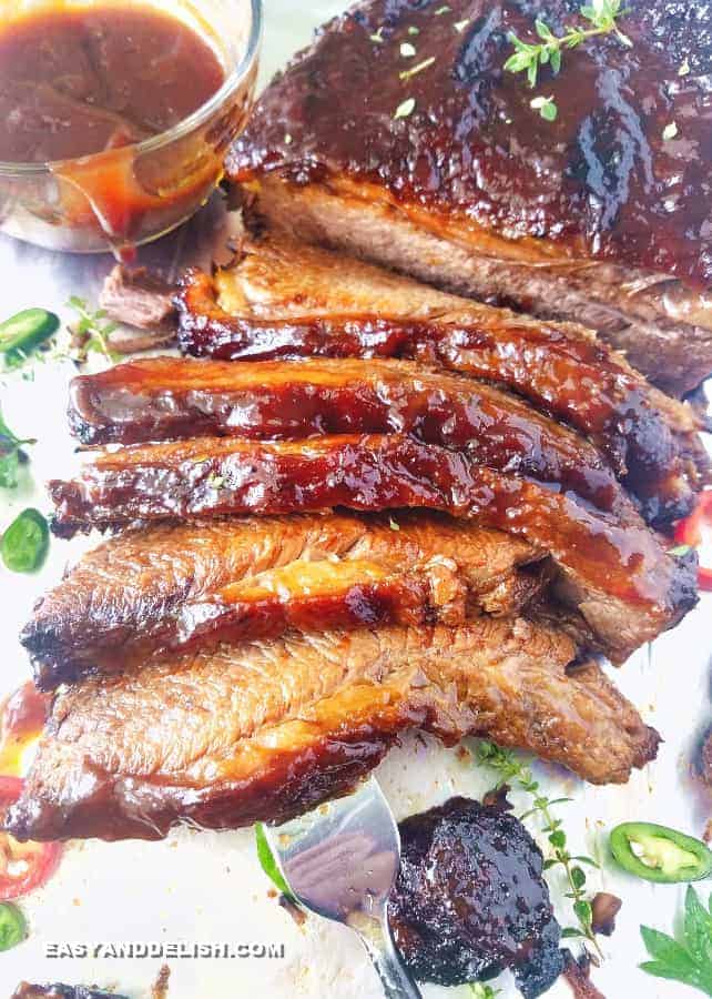 Close up image showing basted meat with bbq sauce in a sheet pan