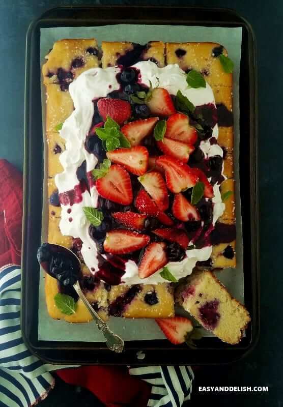 baked good in a baking sheet topped with whipped cream and berries