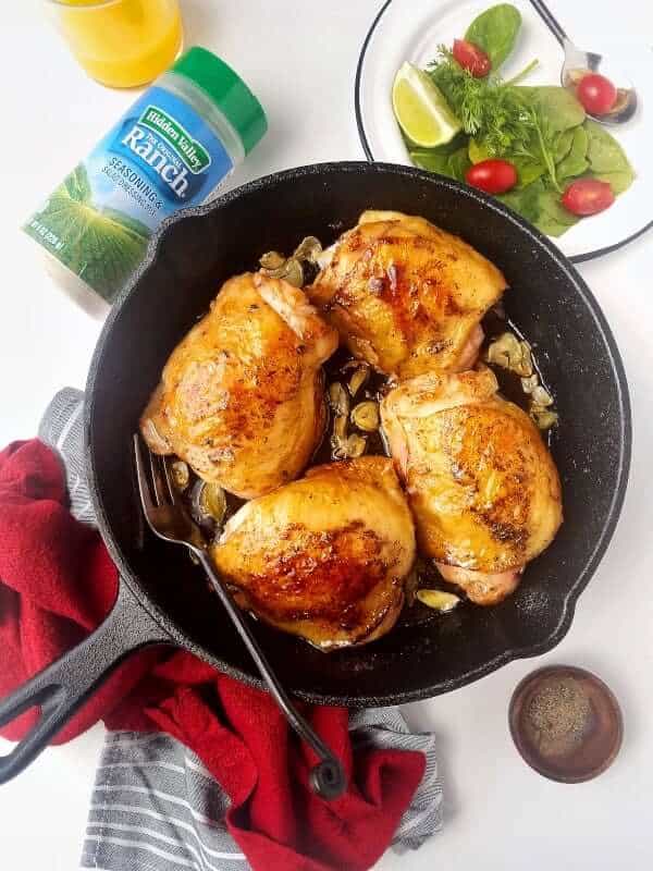 keto ranch chicken in a cast iron skillet with salad and garnishes on the side