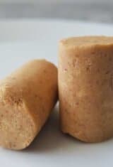 Two pieces of Brazilian pacoca peanut candy, in the traditional cylindrical shape, on a white plate