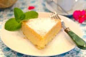 A triangular slice of bolo de fubá or Brazilian cornmeal cake on a plate with a fork and mint garnish