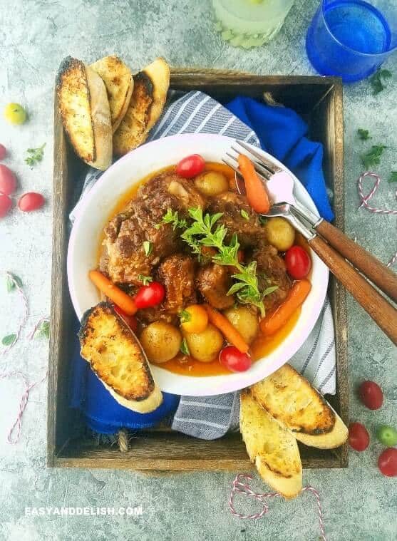 stew in a bowl and tray with bread and drinks on the side