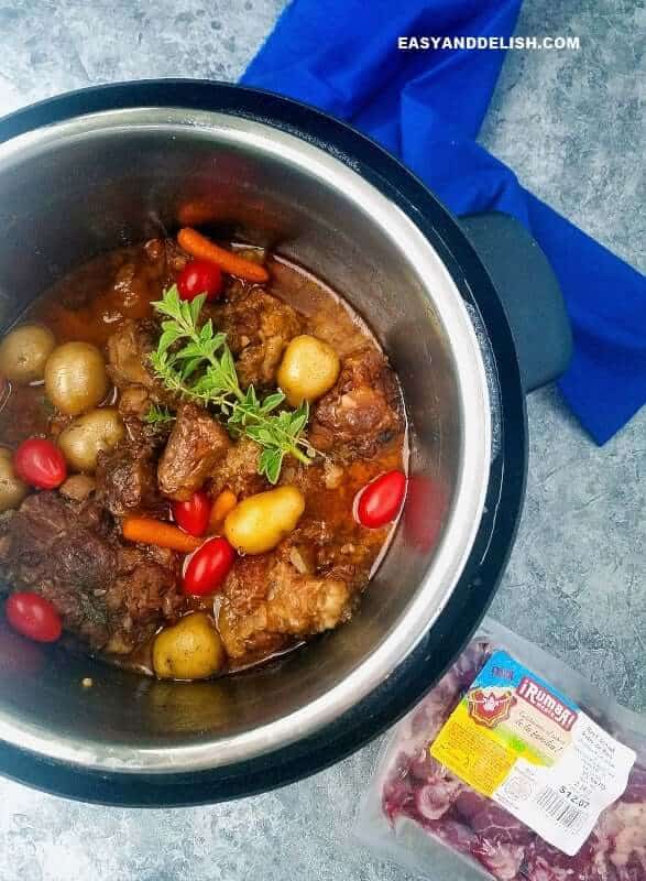 cooked oxtail recipe with raw package of meat on the side of an Instant Pot