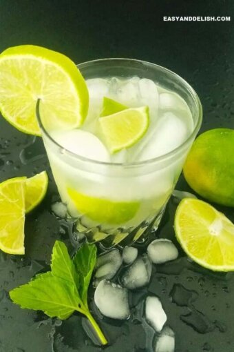 a glass of Caipirinha with lime wedges