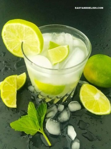 a glass of Caipirinha with lime wedges