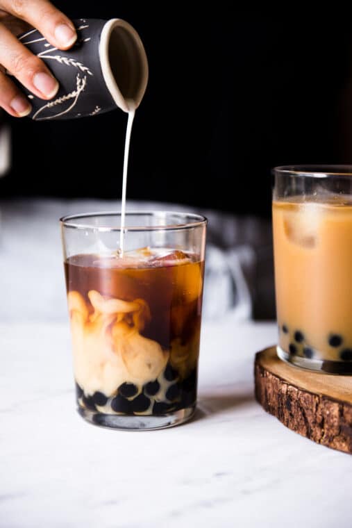 milk being poured in a glass of bubble tea