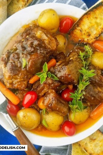 close up of a bowl of beef oxtail with veggies and toast
