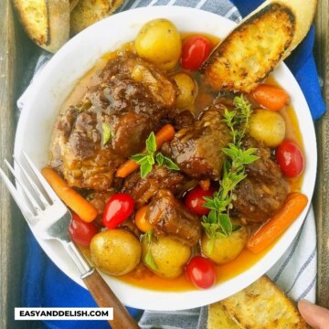 close up of a bowl of beef oxtail with veggies and toast