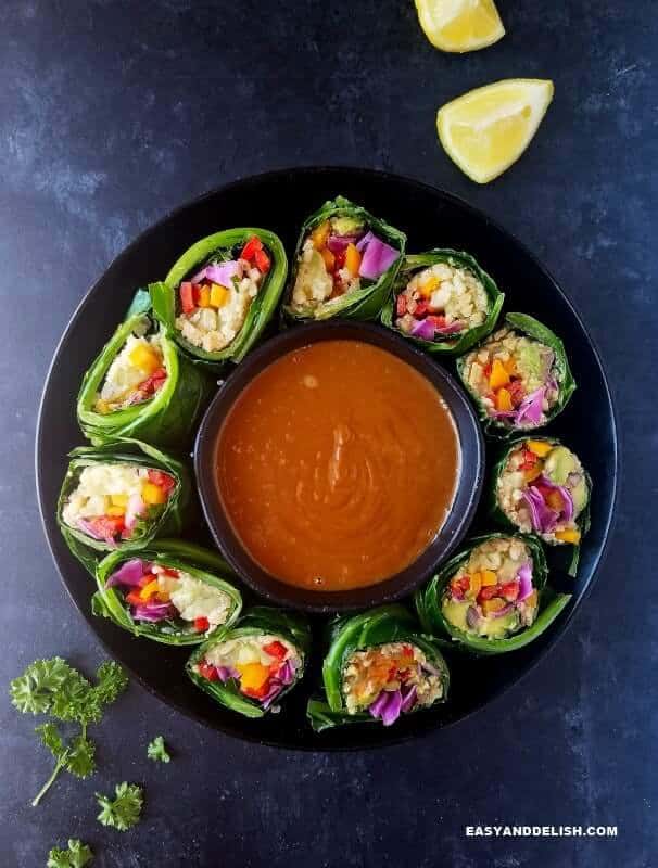 a bowl of collard green wraps with peanut sauce and garnishing on the side