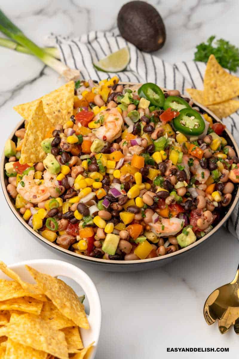 avocado, lime wedges, and chips around a bowl of the Texas Caviar Salad