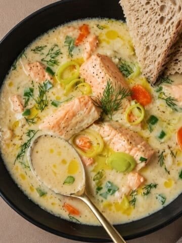 Creamy fish soup in a black bowl.