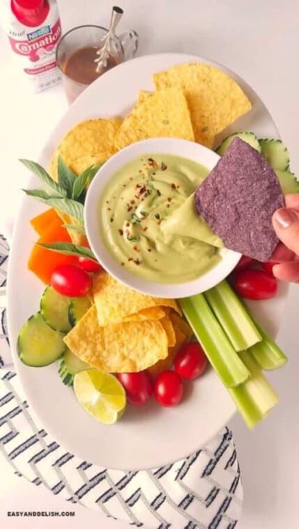 dipping a tortilla chip into a bowl of the best avocado dip 