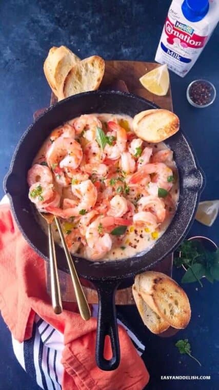 a skillet of keto shrimp scampi with hard-crusted bread on the side