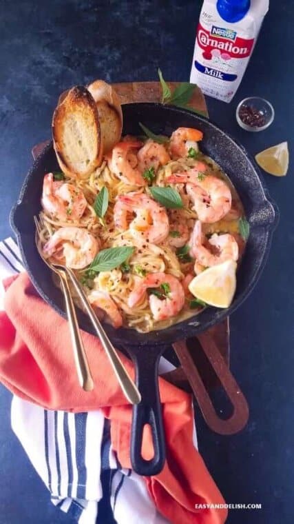 serving homemade creamy shrimp scampi over pasta with bread on the side