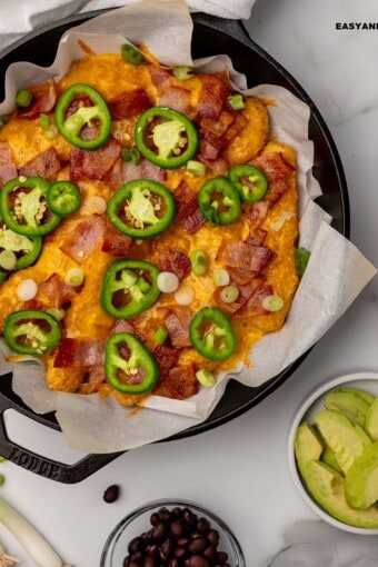 keto nachos in a skillet with some toppings on the side