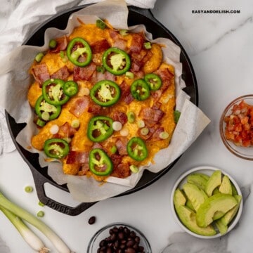 keto nachos in a skillet with some toppings on the side