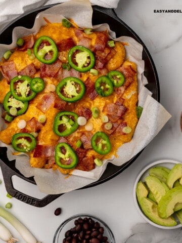 keto nachos in a skillet with some toppings on the side