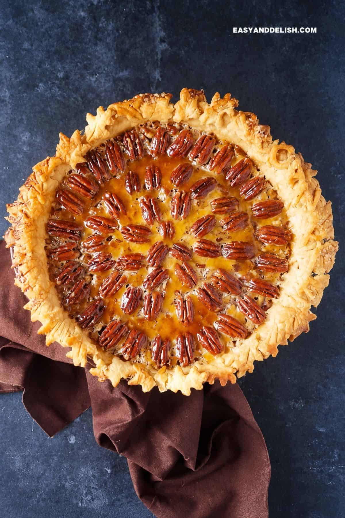Whole Texas pecan pie with glossy pecans and an ornate baked crust.