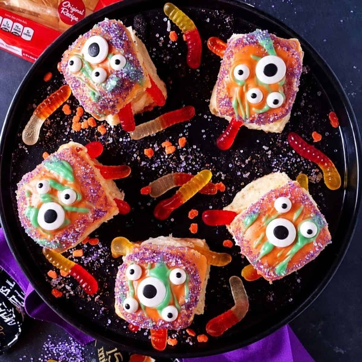 Colorful Halloween monster rolls with candy eyes and gummy worms.