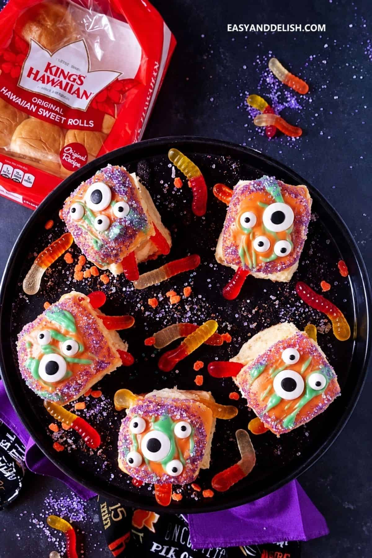 Halloween monster rolls decorated with candy eyes and colorful gummy worms.