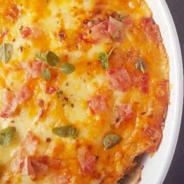 cheesy baked broccoli gratin with bacon in a white dish