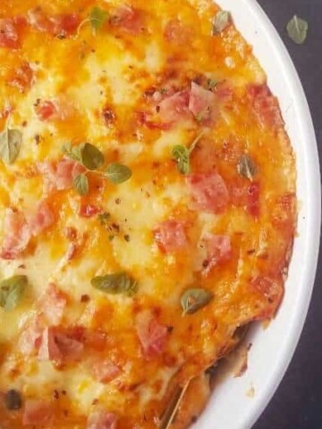 cheesy baked broccoli gratin with bacon in a white dish