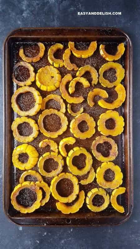 Learn how to cook delicata squash in the oven. It's simple and quick! NO PEELING NEEDED. This roasted delicata squash recipe is vegetarian, low carb, and sugar-free! Simply one of the most comforting ande delicious side dishes ever. #delicatasquash #squash #holidays #thanskgiving #easyrecipe #quickrecipe #roasting #side #lowcarb #vegetarian #sugarfree delicata squash in a baking sheet after being roasted