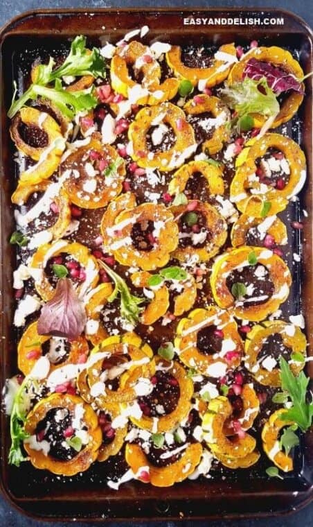 roasted delicata squash in a sheet pan beautifully garnished with yogurt, pomegranate seeds, and herbs