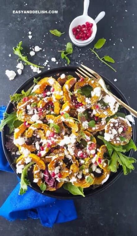 roasted delicata squash in a plate with fork on teh side and agrnishes on the side