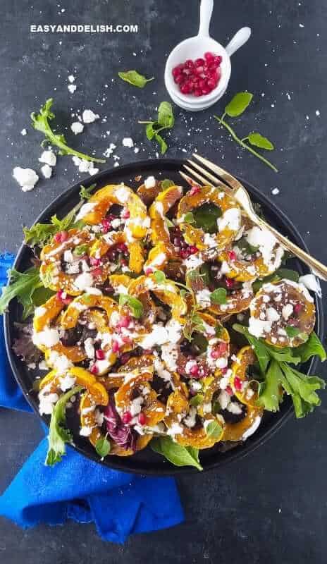 Learn how to cook delicata squash in the oven. It's simple and quick! NO PEELING NEEDED. This roasted delicata squash recipe is vegetarian, low carb, and sugar-free! Simply one of the most comforting ande delicious side dishes ever. #delicatasquash #squash #holidays #thanskgiving #easyrecipe #quickrecipe #roasting #side #lowcarb #vegetarian #sugarfree roasted delicata squash in a plate with fork on teh side and agrnishes on the side