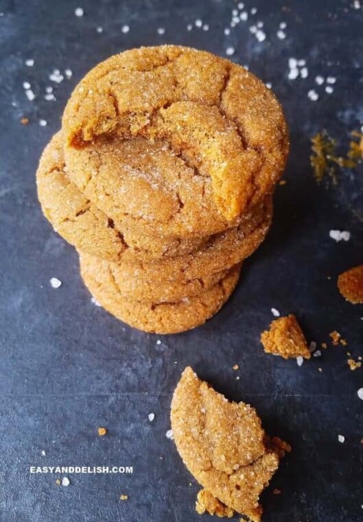 a pile of ginger molasses cookies with crumbles on the side