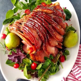 A platter with honey baked ham garnished with pears and veggies