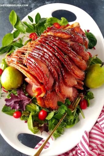 A platter with honey baked ham garnished with pears and veggies