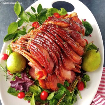 Brown sugar mustard honey glazed ham in a platter with a salad.