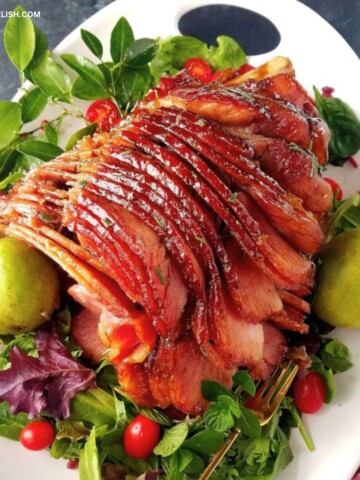 Brown sugar mustard honey glazed ham in a platter with a salad.