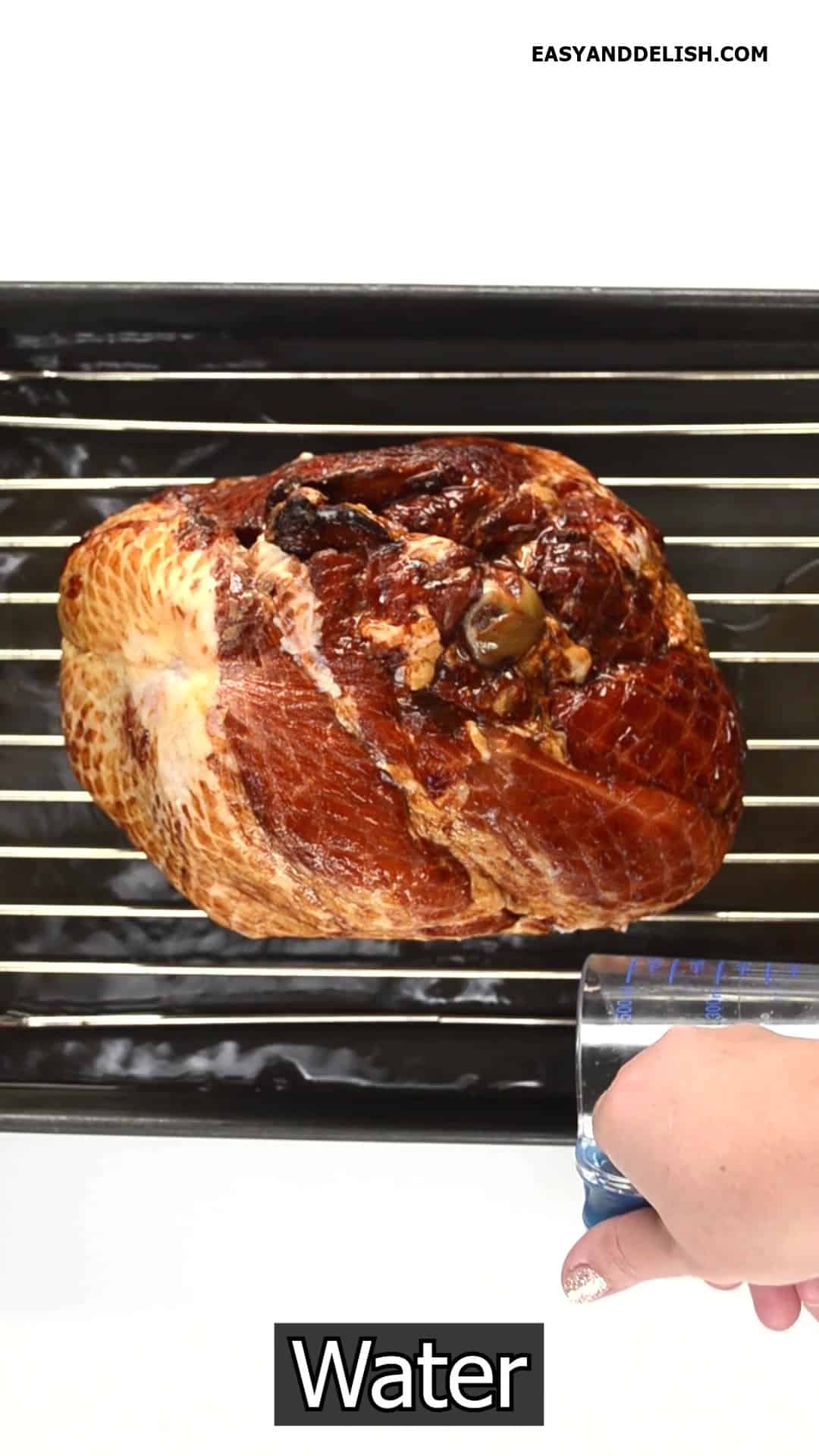 Spiran bone-in ham placed cut face down on a rack of a roasting pan with water poured onto the bottom of the pan.