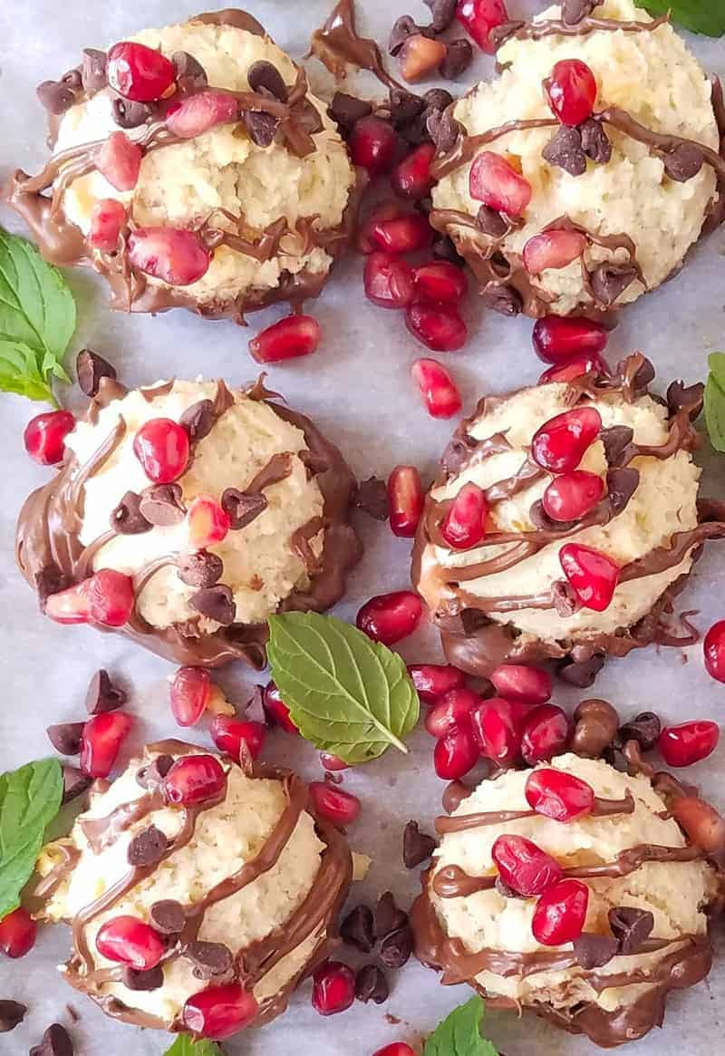 Keto or Low Carb Chocolate Chip Coconut Cookies made with almond flour and no added sugar. They are light, soft, and yummy. Small bites of heaven that are indulgent yet guilt-free! close up image of low carb chocolate chips coconut cookies with pom seeds and chocolate drizzle