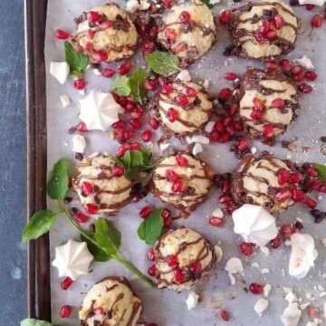 many  low carb chocolate chip coconut cookies drizzled with melted chocolate and garnished with pomegranate seeds in a baking pan