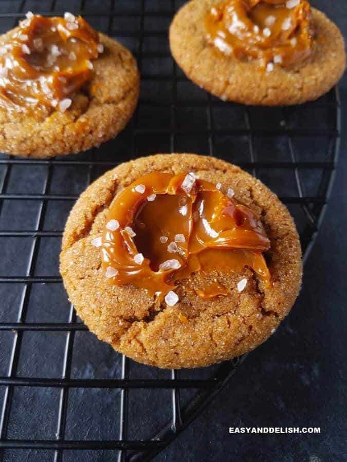 Salted Dulce de Leche Cinnamon Cookies Recipe that is gluten-free and full of warm spices that will comfort your soul. The best molasses cookies ever! #molasses #dulcedeleche #cookies #cinnamon #easyrecipe #christmas #holidays Close up of dulce de leche cinnamon cookies over a rack