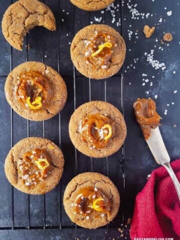 Cinnamon cookies topped with dulce de leche over a rack with coarse salt sprinkles.