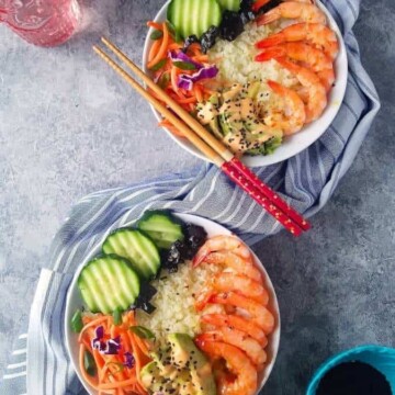 two sushi bowl with a glass of water and chopsticks on the side