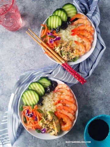 two sushi bowl with a glass of water and chopsticks on the side