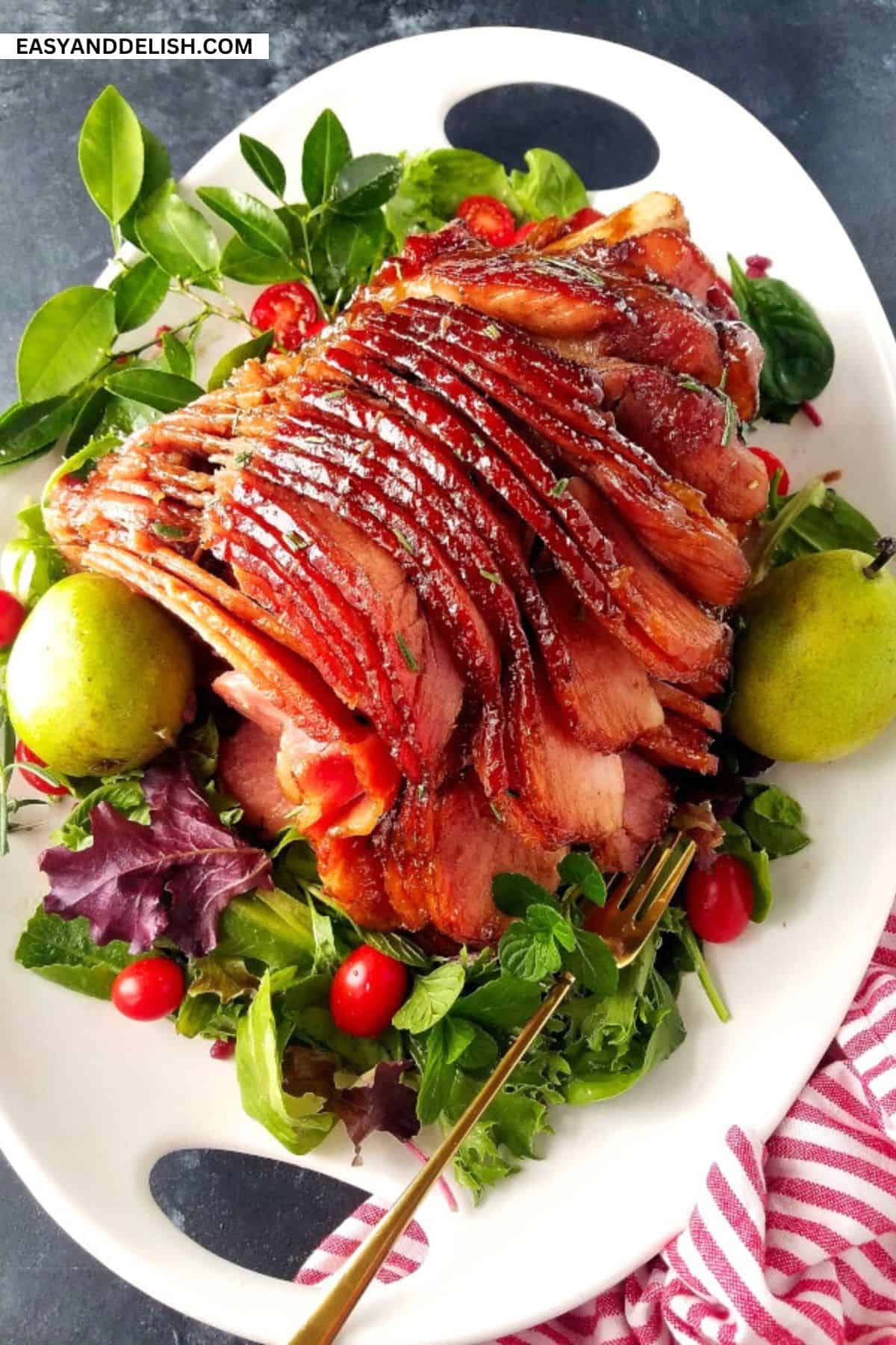 Honey baked glazed ham in a platter with some seasonal garnishes.