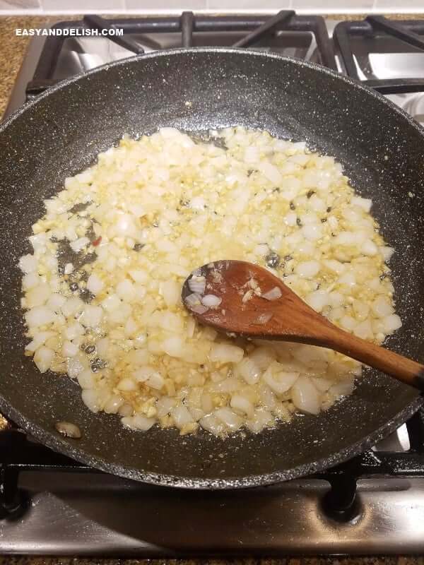 sauteeing garlic and onion in a skillet to make vegetarian feijoada on the stovetop