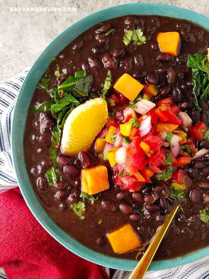 A bowl of vegetarian feijoada with garnishes on top a sour of our easy beans recipes