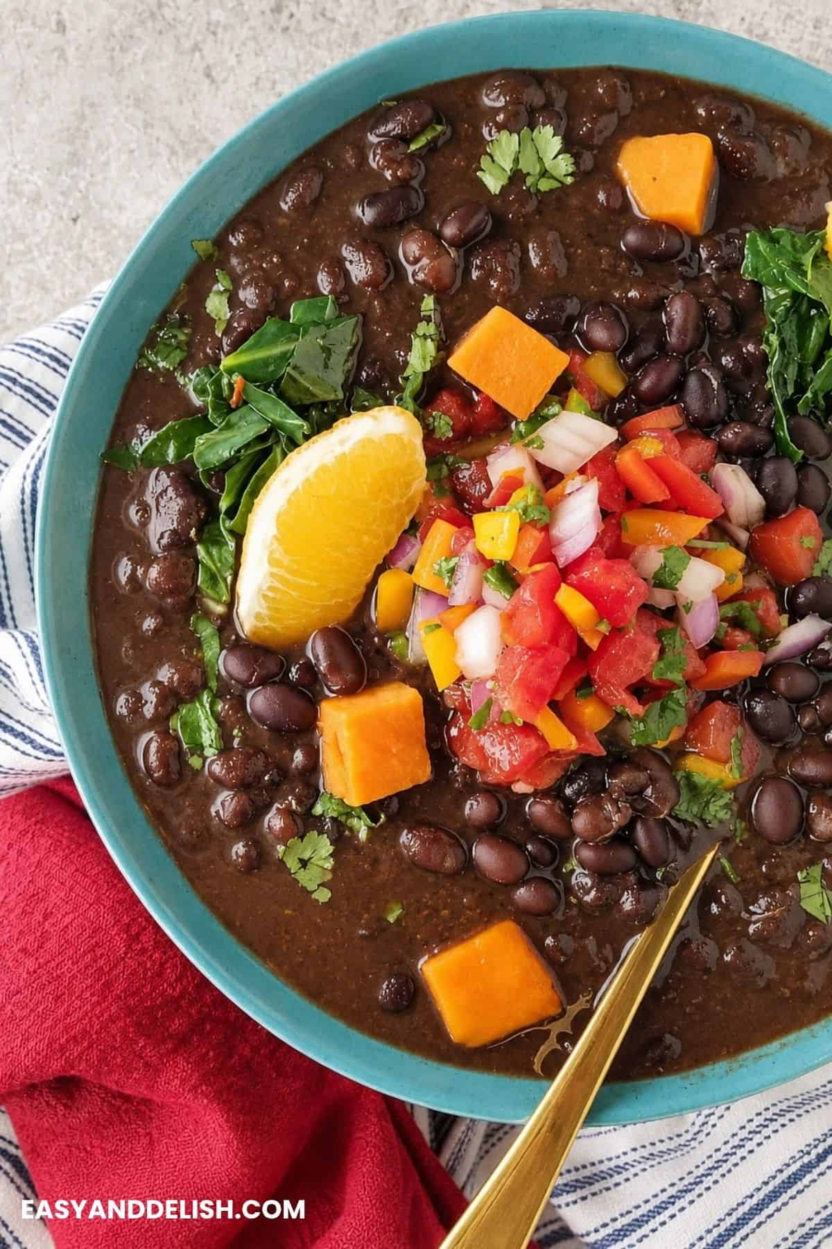 Brazilian black bean stew with sweet potatoes, greens, fresh salsa, and orange wedges.