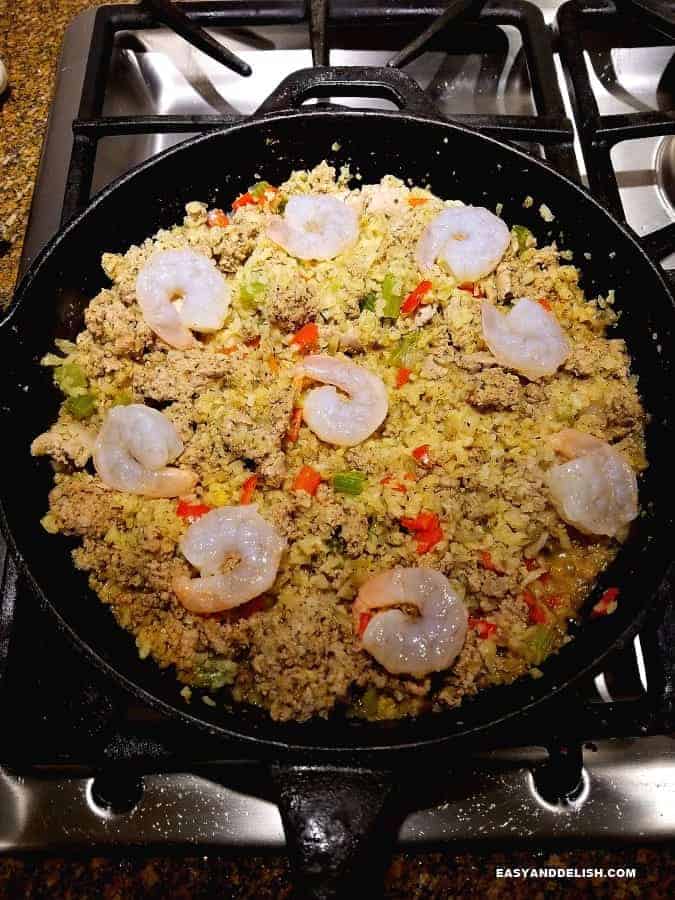 cajun rice cooking in a skillet with shrimp on top