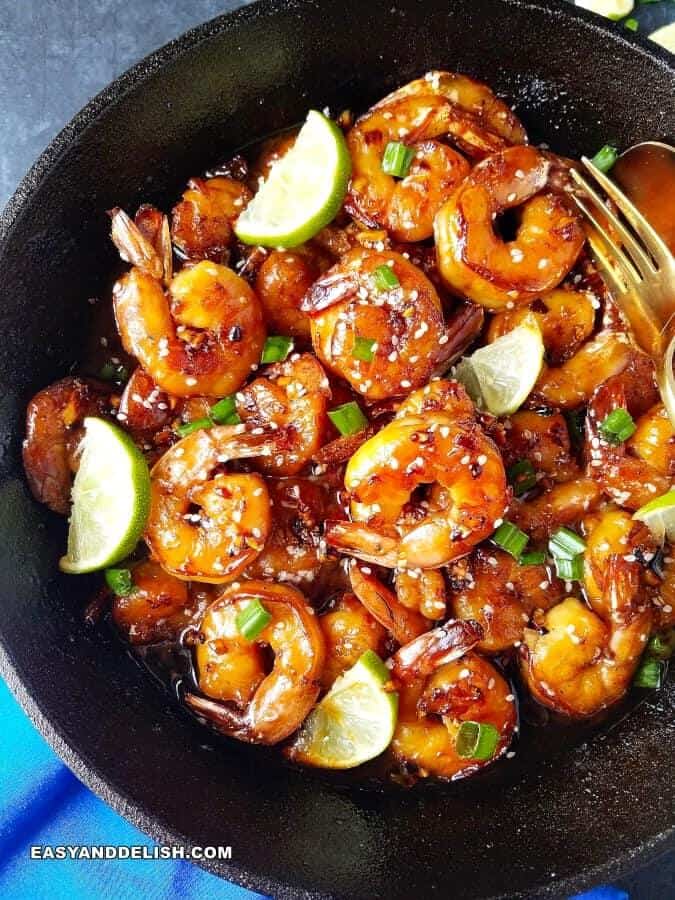 garlic butter shrimp in a skillet with wegges of lime